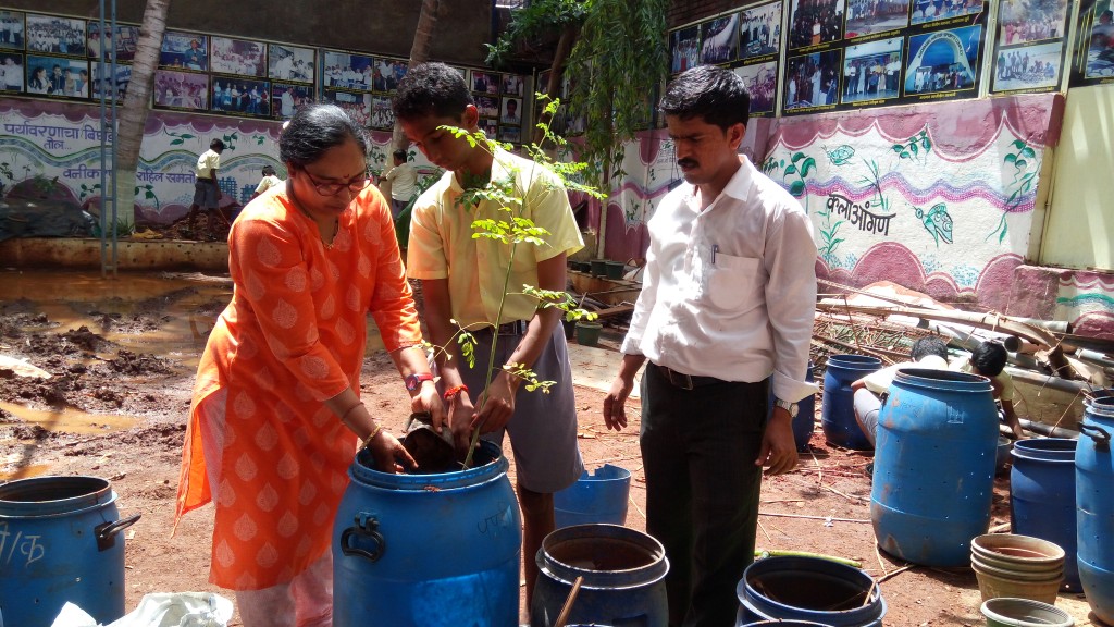 Sangeeta på Srushtidnyan planterar drumstick tillsammans med lärare och elev. Foto: Srushtidnyan